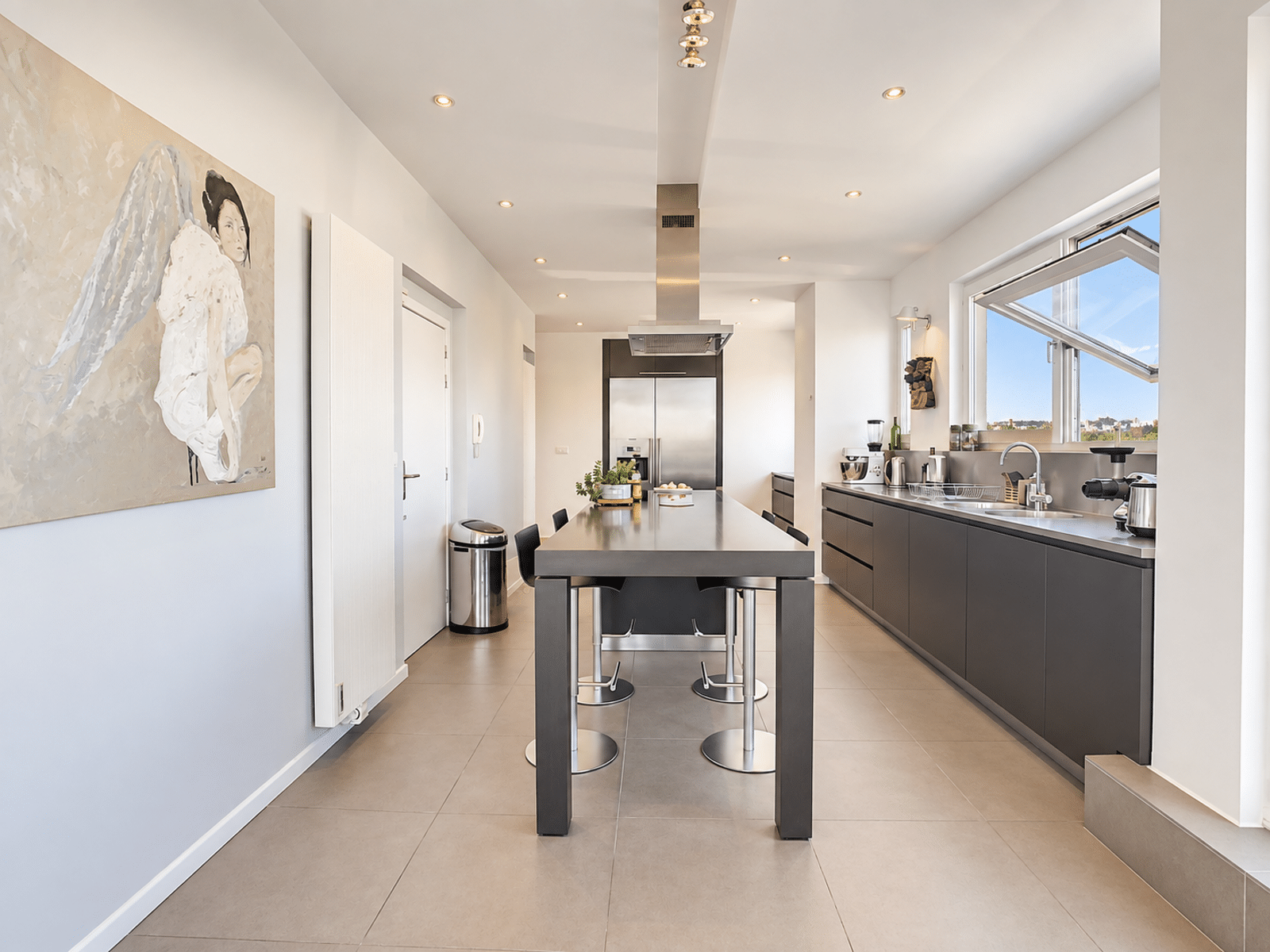 Cuisine Moderne avec Îlot Central – You Real Estate Agency Cuisine moderne en longueur avec îlot central dans un appartement lumineux.