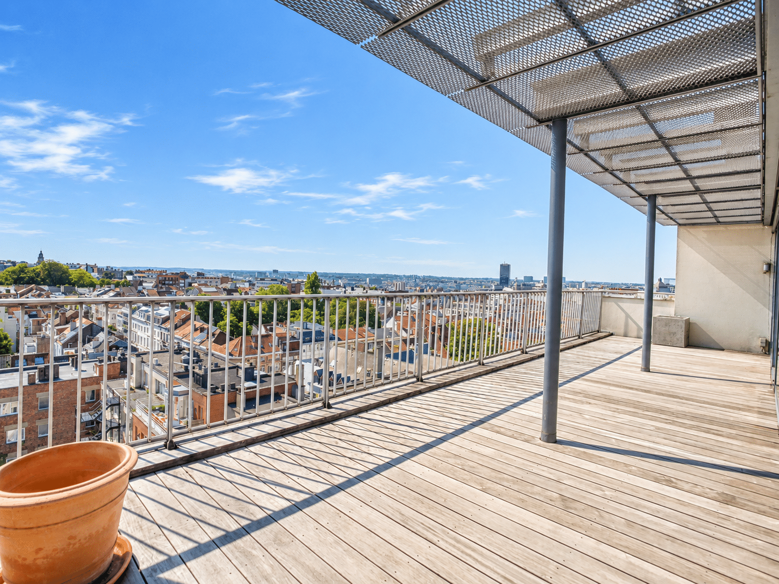 Terrasse Rooftop avec Vue Panoramique – You Real Estate Agency Terrasse rooftop d’appartement avec vue panoramique sur quartier urbain.