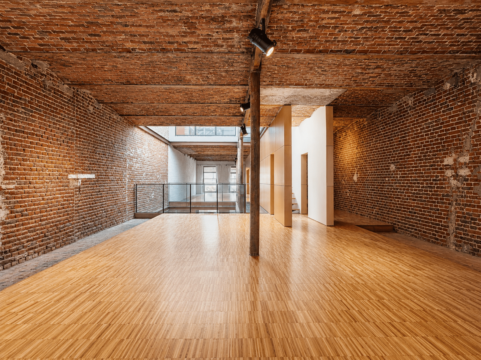 Loft Rénové avec Briques Apparentes – You Real Estate Agency Loft rénové avec murs en briques apparentes, parquet clair et mezzanine vitrée.