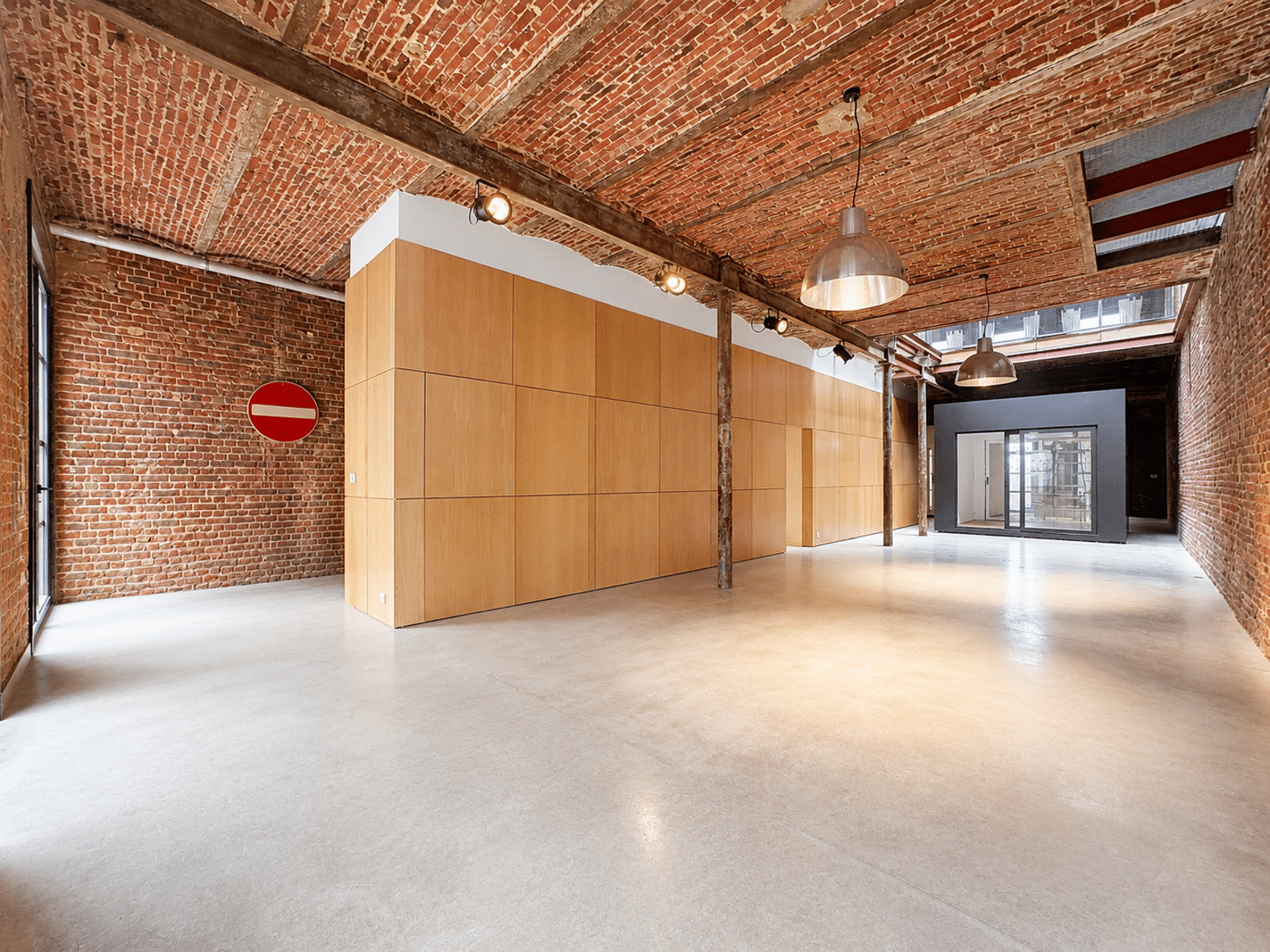 Espace Ouvert de Style Loft Industriel – You Real Estate Agency Appartement loft industriel avec murs en briques, plafond voûté et grande pièce ouverte.
