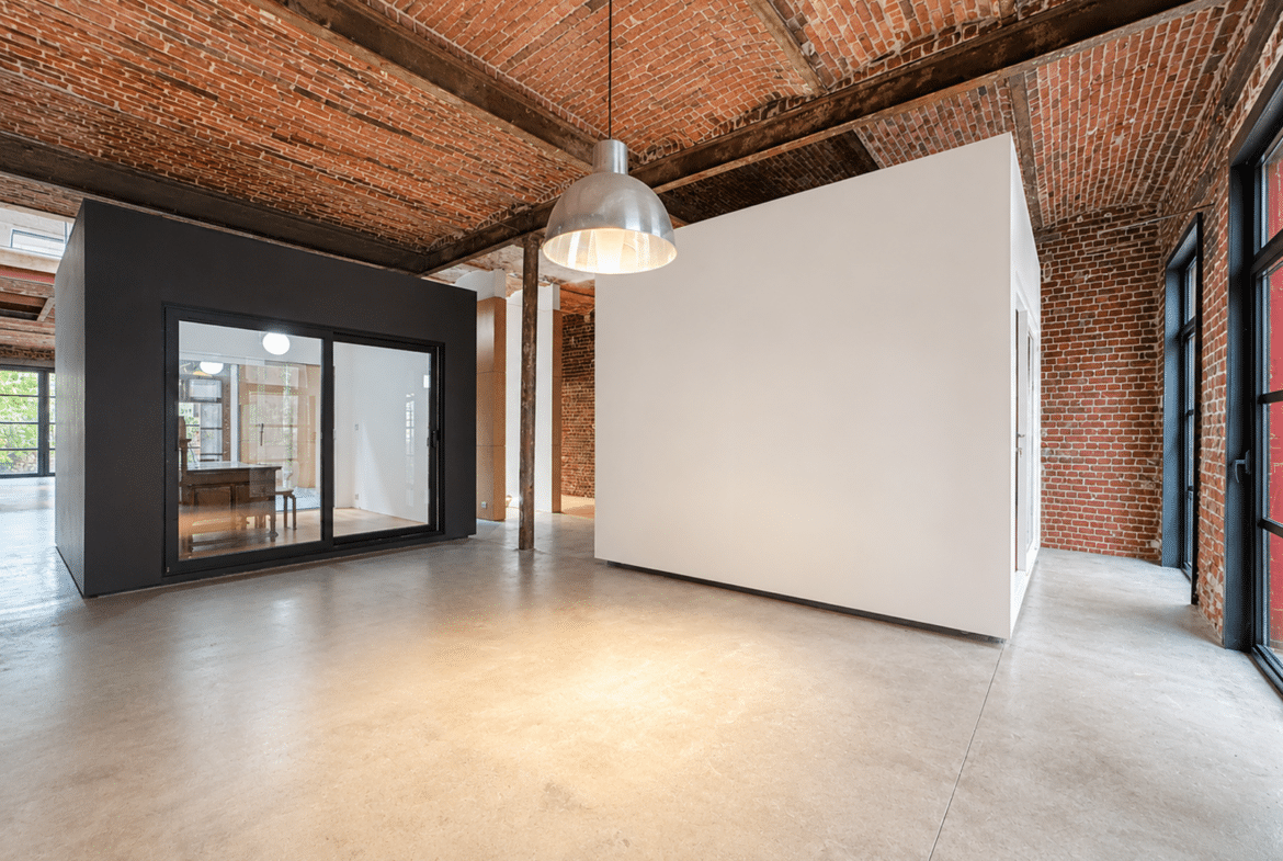Salon de loft industriel rénové avec plafond voûté en briques et volumes modernes.