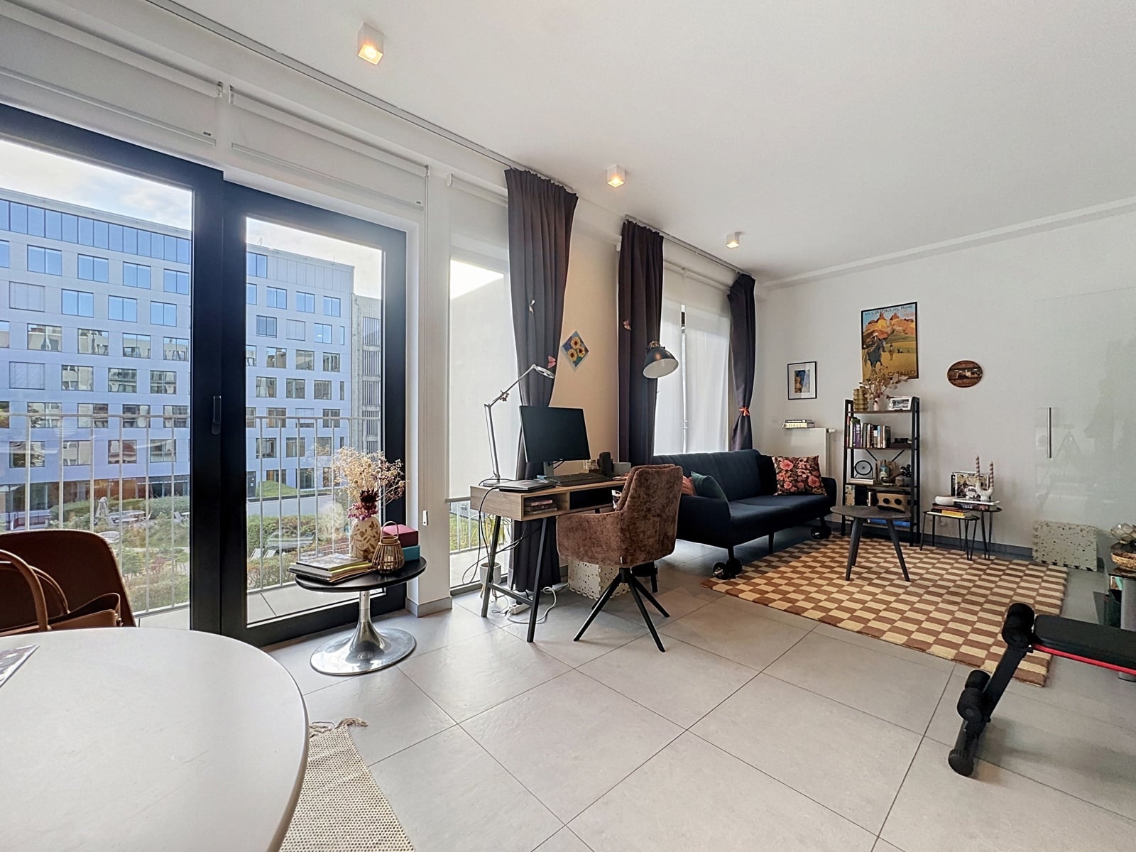 whise photo 7 Bright living room with large glass doors to a balcony, a home office setup by the window, and a cozy seating area.