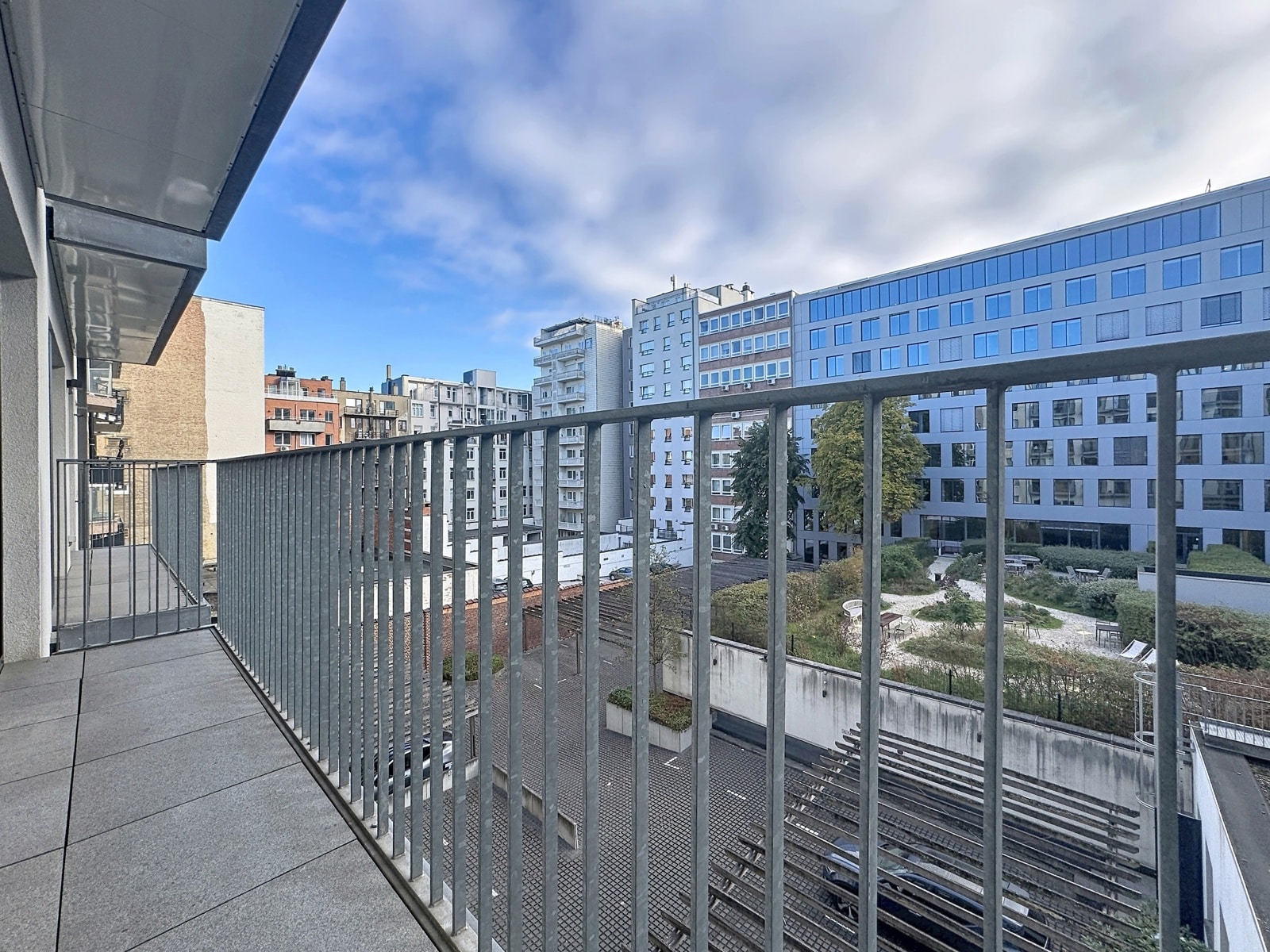 Balcon Moderne avec Vue sur Cour – You Real Estate Agency Terrasse d’appartement moderne avec vue sur cour intérieure et immeubles urbains.