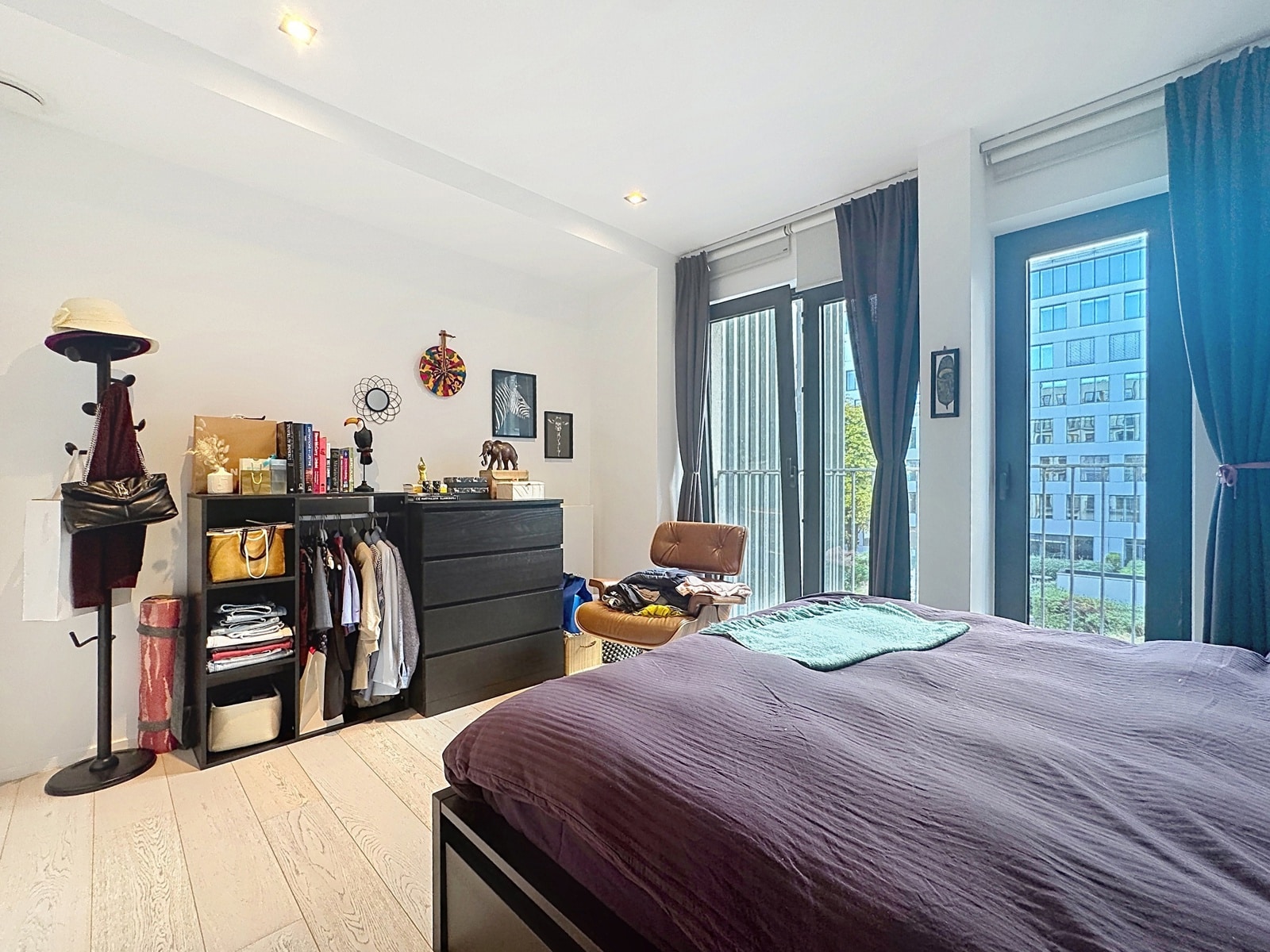 Chambre Lumineuse avec Baies Vitrées – You Real Estate Agency Chambre lumineuse d’appartement moderne avec lit double, rangements et grandes baies vitrées.