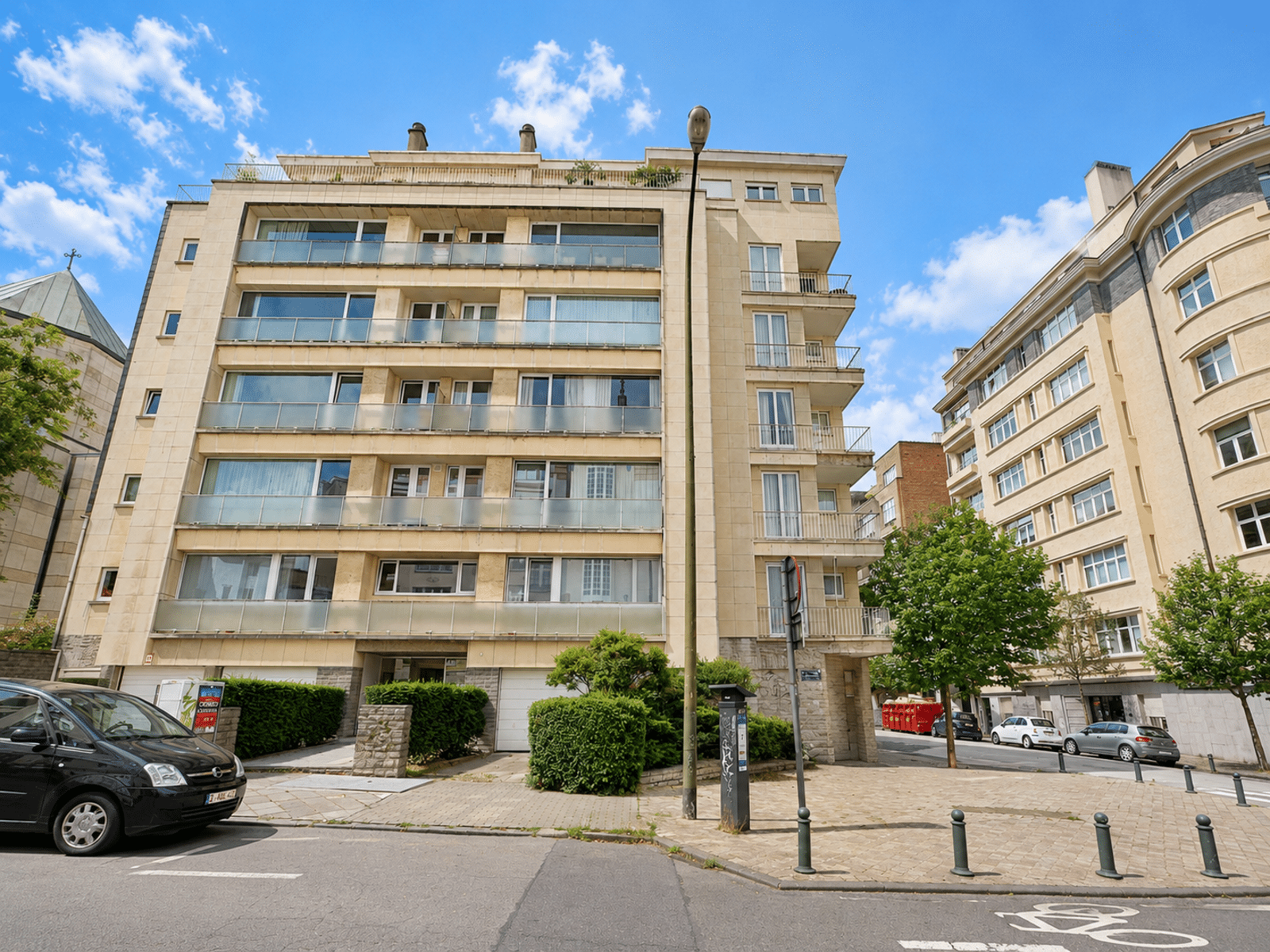 Moderne woongevel – You Real Estate Agency Modern woongebouw met appartementen en terrassen aan de voorzijde, in een rustige straat.