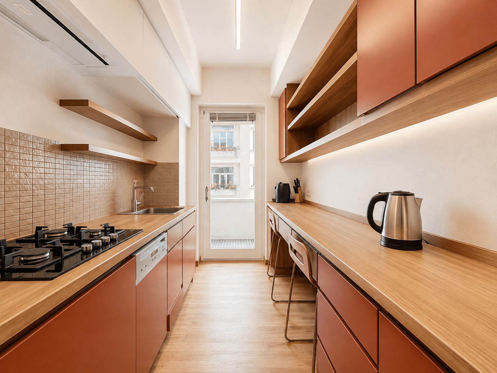 Moderne, volledig ingerichte keuken in de lengte – You Real Estate Agency Moderne, in de lengte opgestelde inbouwkeuken met houten werkbladen in een licht appartement.
