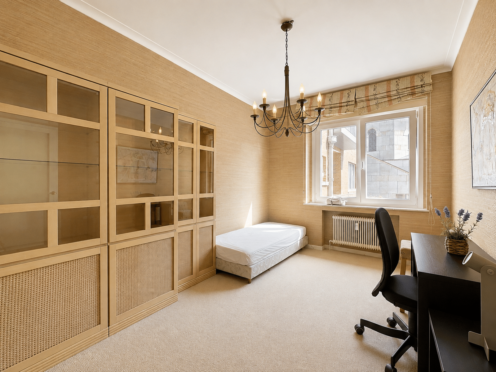 Lichte slaapkamer/werkkamer met inbouwkasten – You Real Estate Agency Lichte slaap- en werkkamer met inbouwkasten en een eenpersoonsbed in een appartement.
