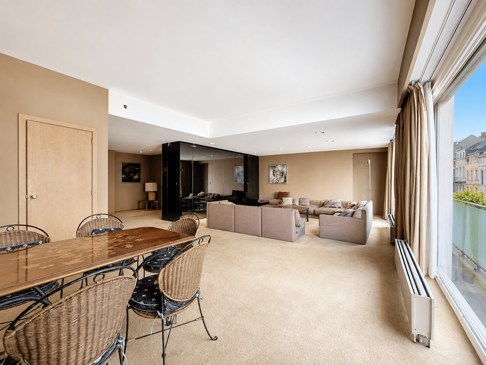 Lichte woonkamer met erkers - You Real Estate Agency Lichte woonkamer met eethoek en grote ramen in een stadsappartement.