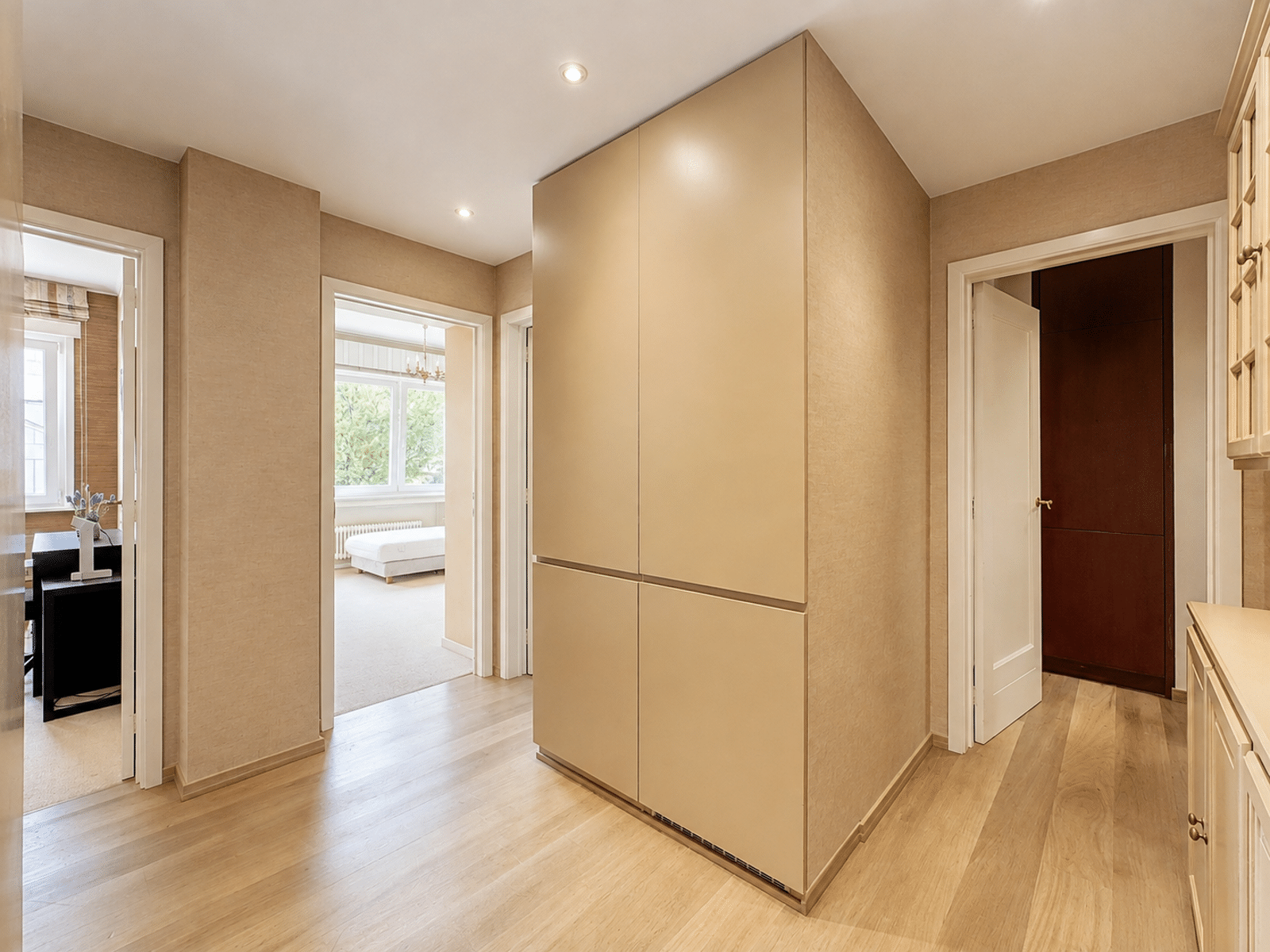 Lichte hal met opbergruimte – You Real Estate Agency Lichte hal met ingebouwde opbergruimte en parketvloer in een moderne woning.