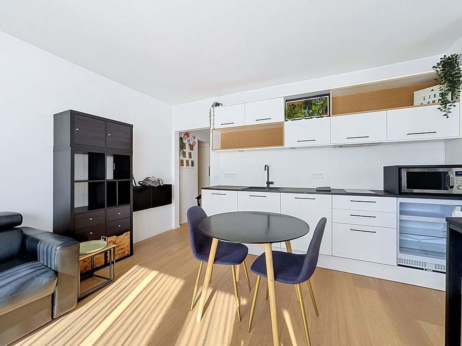 Séjour Ouvert avec Cuisine Moderne – You Real Estate Agency Appartement lumineux avec salon ouvert, cuisine moderne blanche et table à manger.