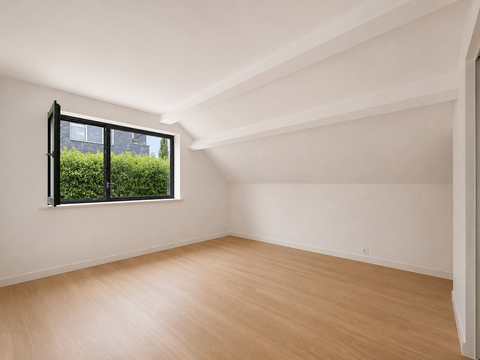 whise photo 8 Bright, empty attic room with white walls, light wood flooring, and a large black-framed window open to green bushes outside.