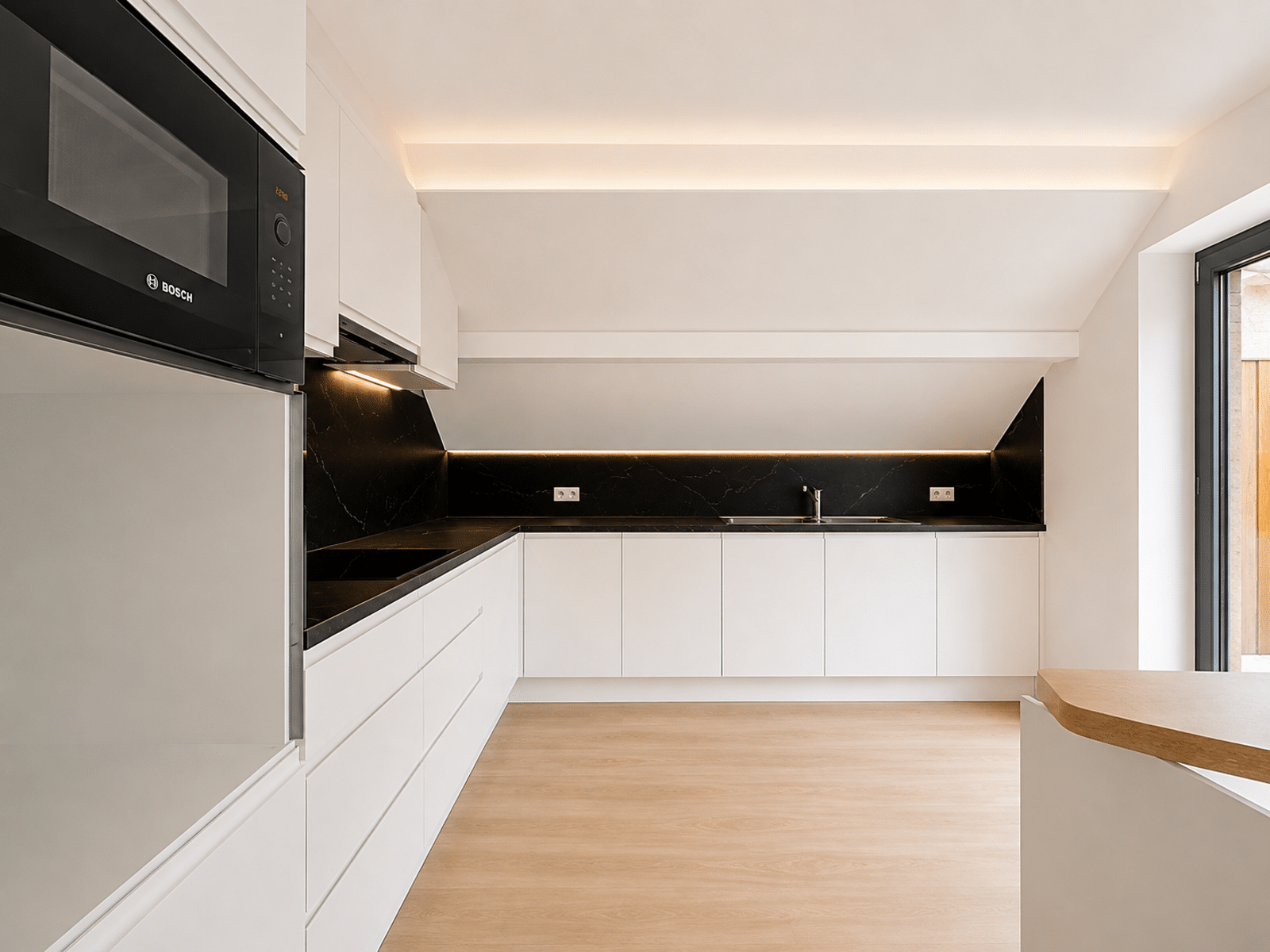 whise photo 5 Modern minimalist kitchen with white cabinets, black marble counter backsplash, built-in oven and microwave, and under-cabinet lighting across the back wall.