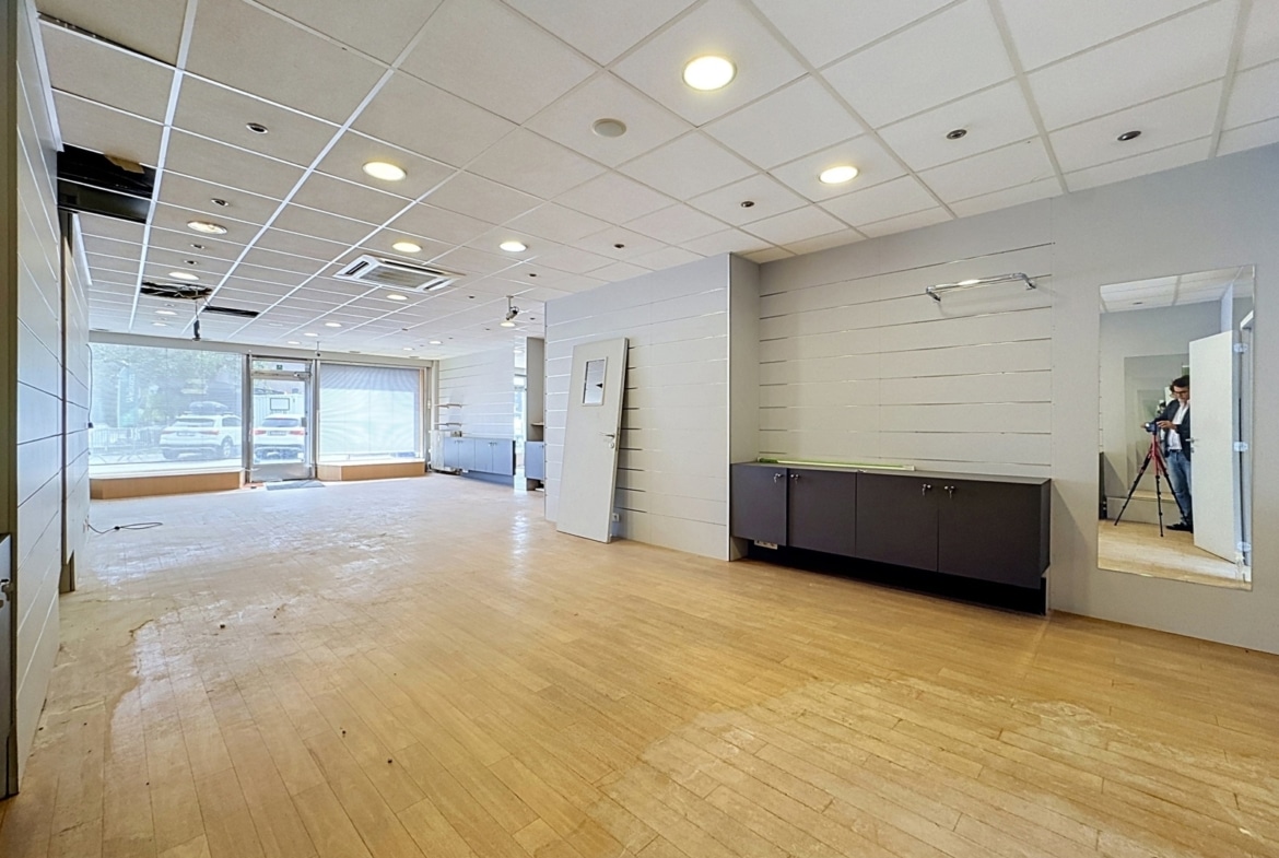 Local commercial vacant lumineux avec parquet, vitrines et mobilier intégré.