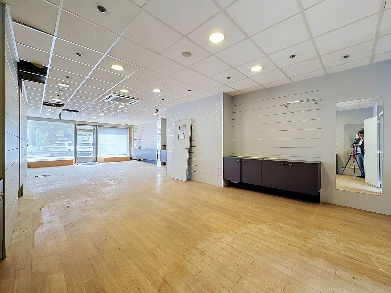 Espace Commercial Lumineux À Rénover – You Real Estate Agency Local commercial vacant lumineux avec parquet, vitrines et mobilier intégré.