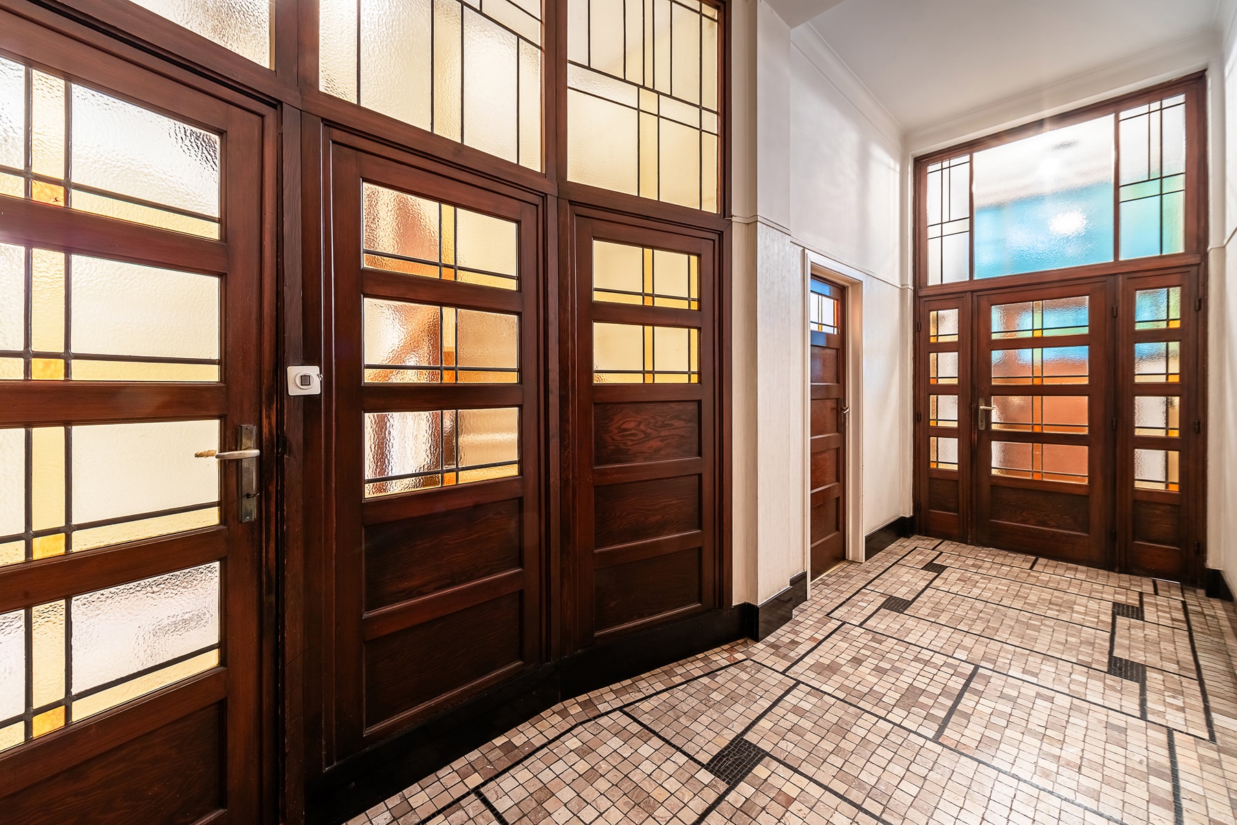 whise photo 5 Wooden paneled doors with frosted glass windows lining a tiled hallway.