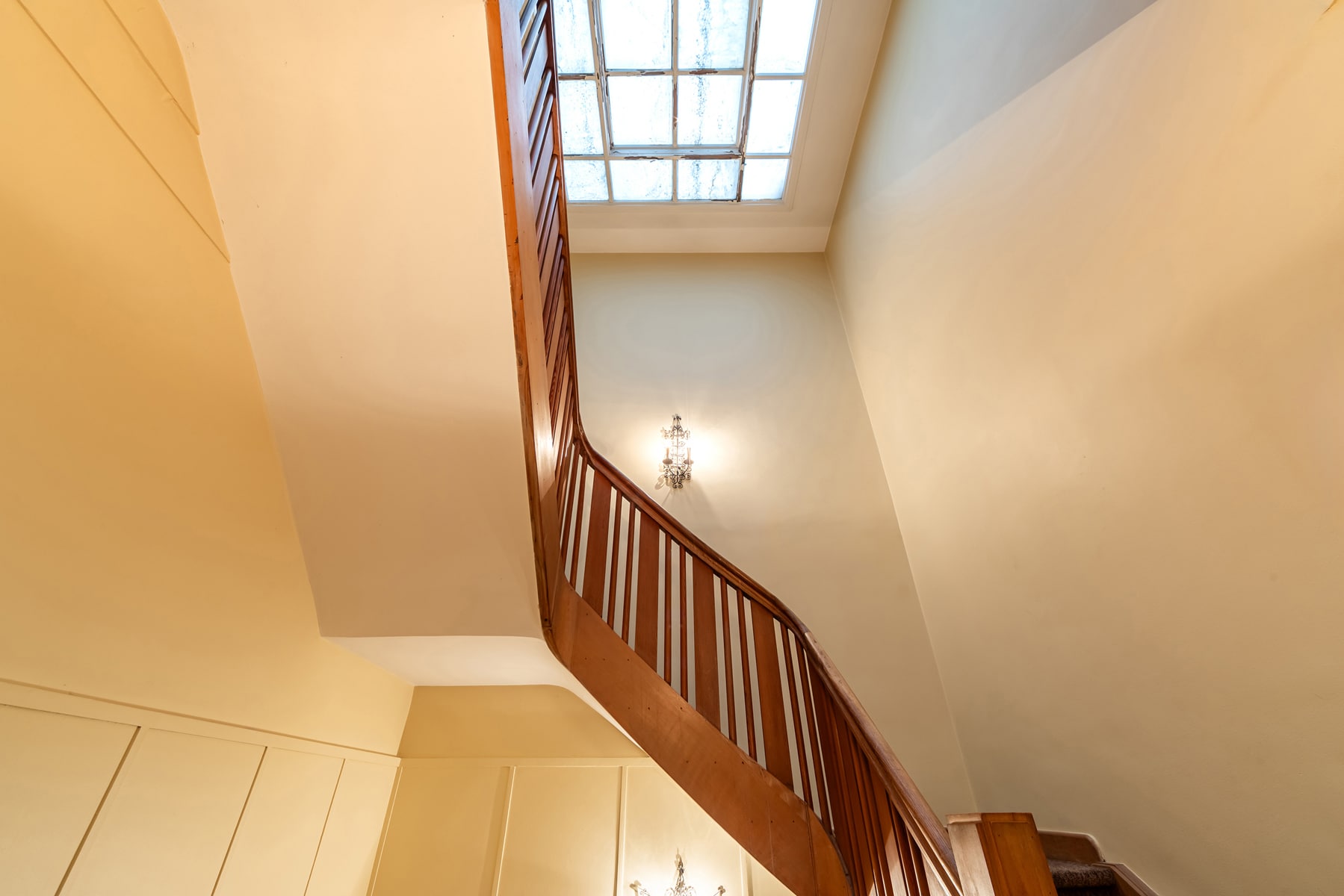 Interior Staircase with Glass Roof – You Real Estate Agency An elegant interior staircase with a skylight in a charming home.