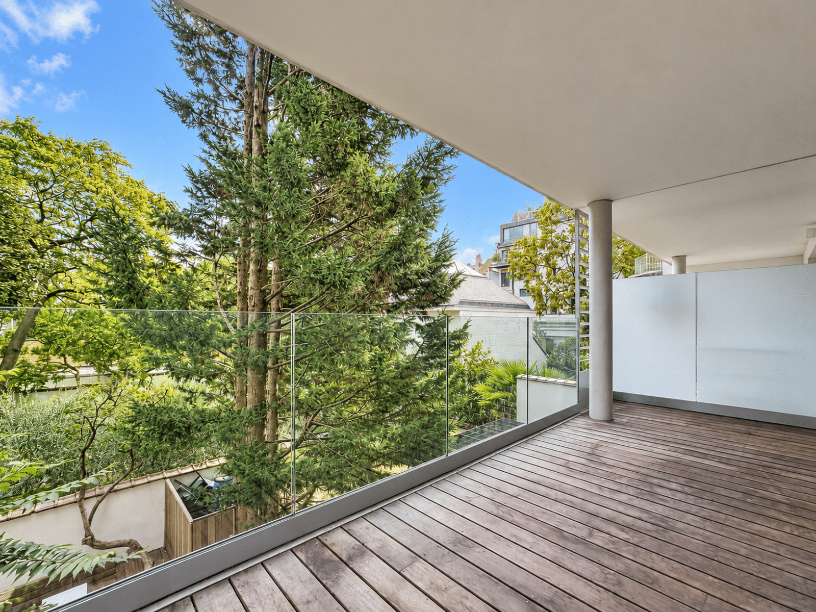 Terrasse Moderne avec Vue Verdoyante – You Real Estate Agency Grande terrasse d’appartement moderne avec parquet bois et vue verdoyante.