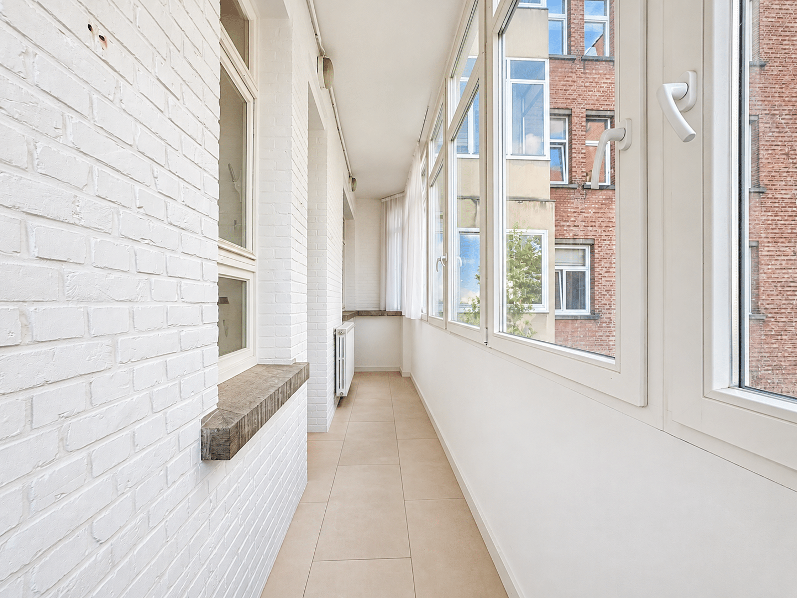 Balcon Fermé Avec Baies Vitrées – You Real Estate Agency Balcon fermé lumineux d’appartement avec baies vitrées et carrelage beige.