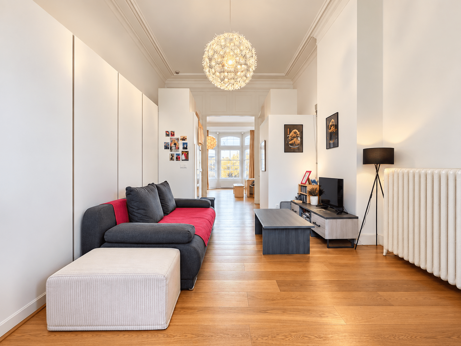 Salon Lumineux Aux Hauts Plafonds – You Real Estate Agency Salon lumineux d’appartement moderne avec parquet, hauts plafonds et espace TV.