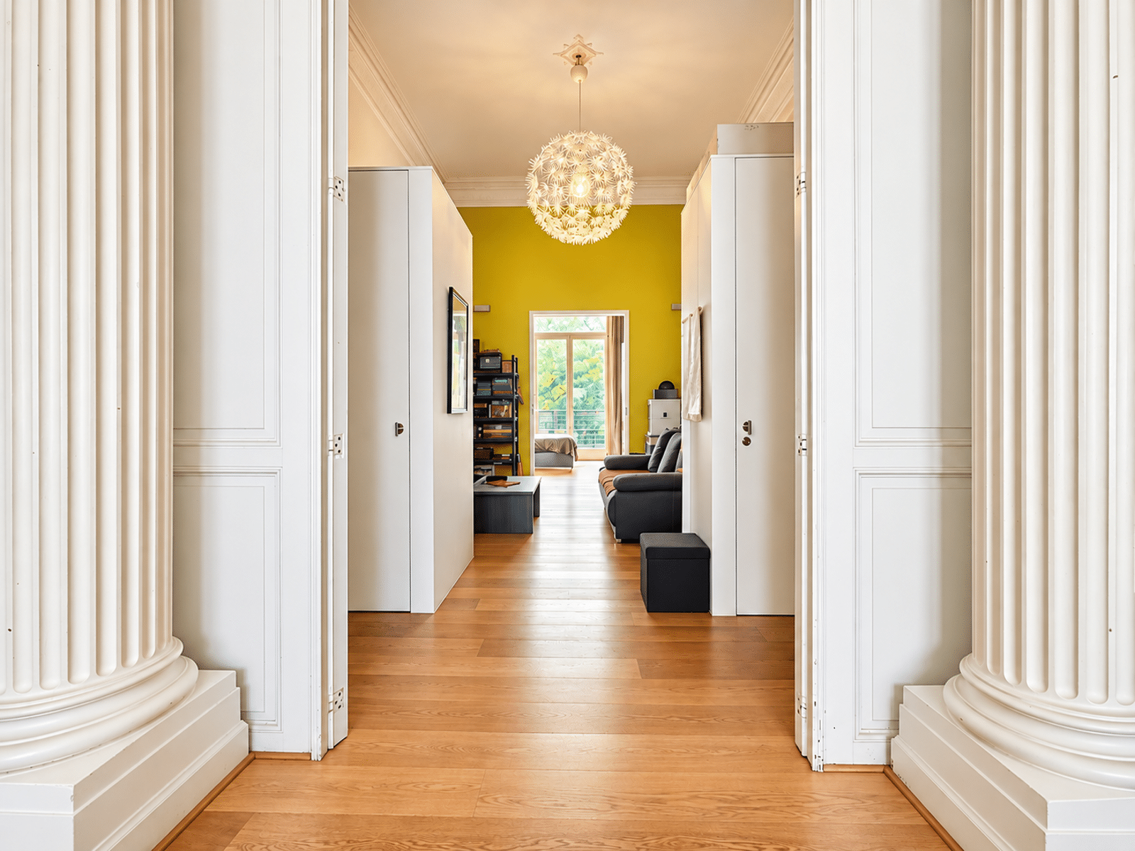 Salon Lumineux avec Colonnes – You Real Estate Agency Appartement lumineux avec salon, parquet, colonnes classiques et balcon verdoyant.
