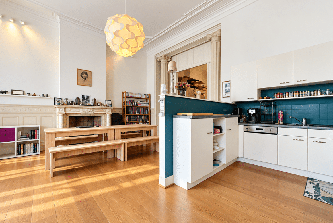 Appartement lumineux avec cuisine ouverte, salon, parquet, moulures et cheminée décorative.