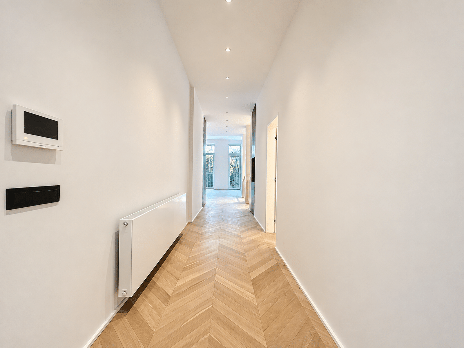Couloir Moderne avec Parquet Chevrons – You Real Estate Agency Couloir lumineux d’appartement moderne avec parquet en chevrons et fenêtres.