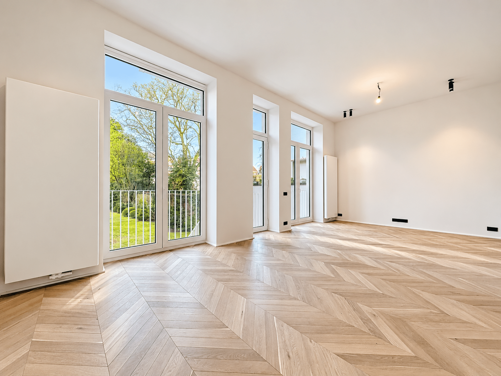 whise photo 3 Bright empty living room with large glass doors to a fenced yard and a herringbone wood floor