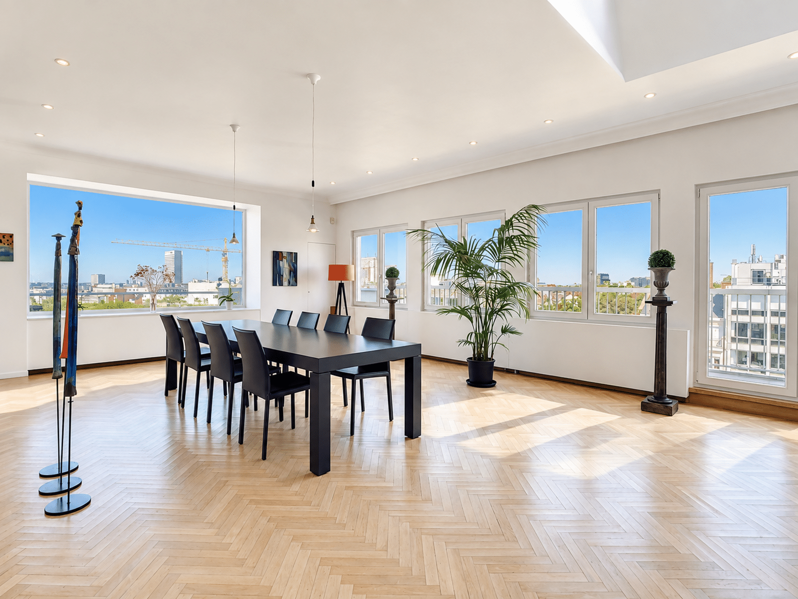 Salle à Manger Moderne et Lumineuse – You Real Estate Agency Salle à manger lumineuse d’appartement moderne avec parquet, grandes fenêtres et vue urbaine.