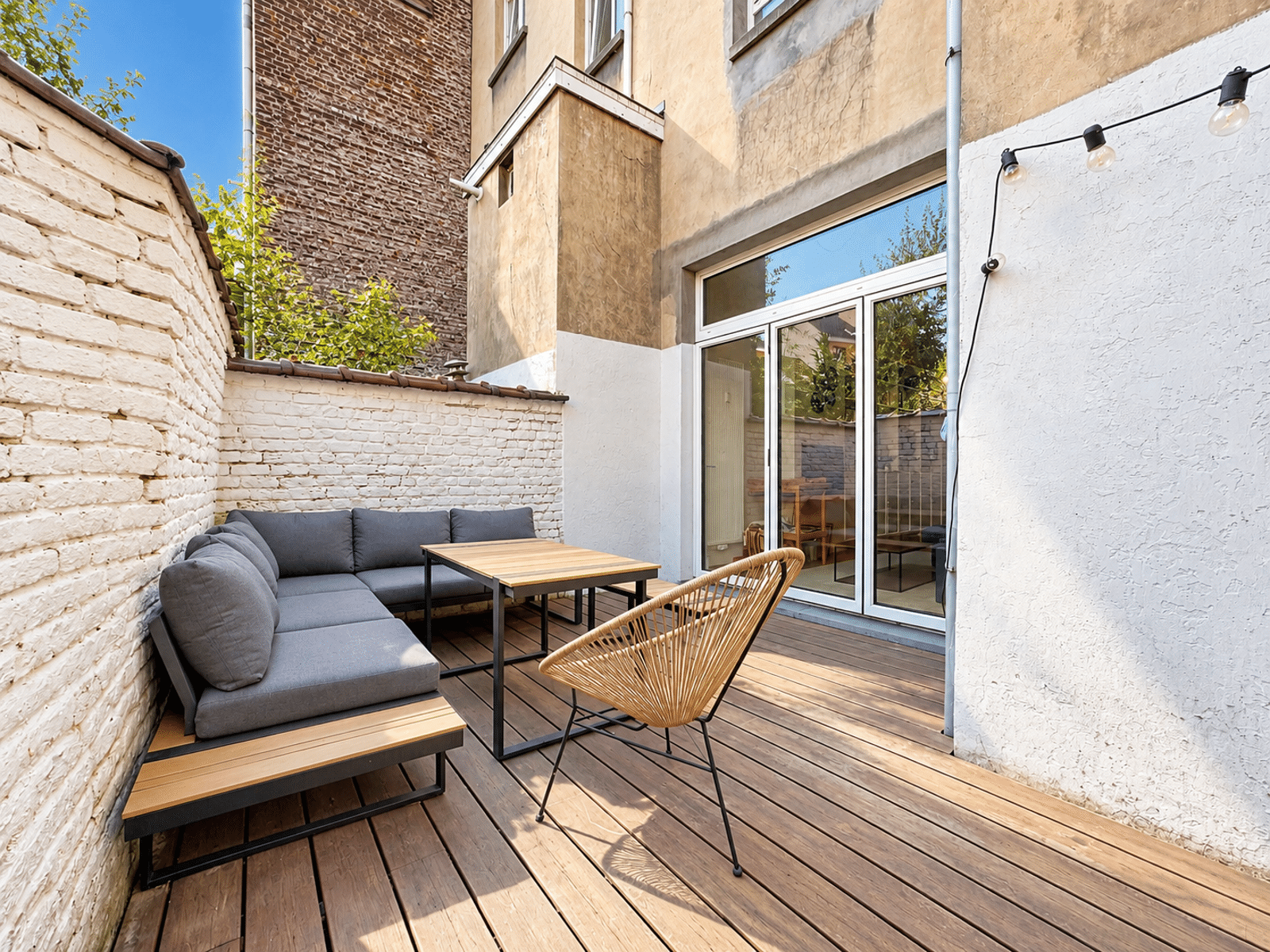 Binnenpatio met tuinmeubilair – You Real Estate Agency Houten binnenterras met moderne tuinmeubels in een herenhuis.
