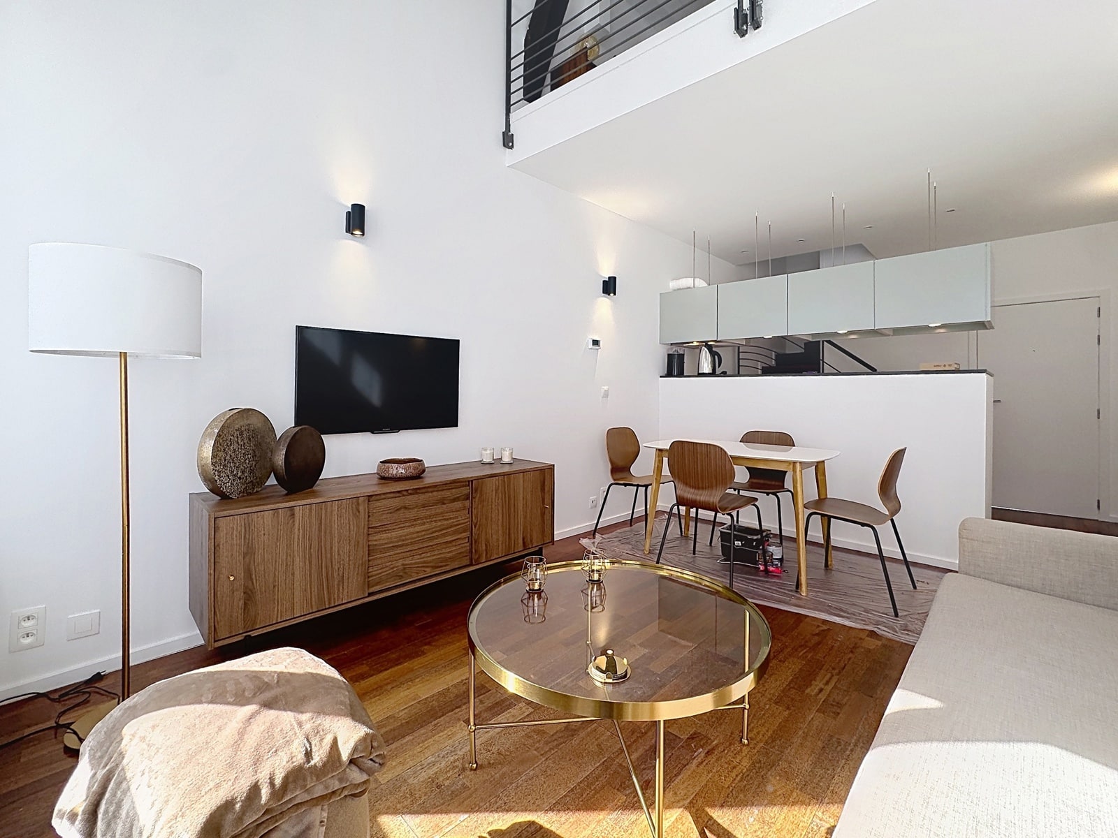 whise photo 2 Open-concept living room with wall-mounted TV, wooden sideboard, round glass coffee table, and a white sofa.