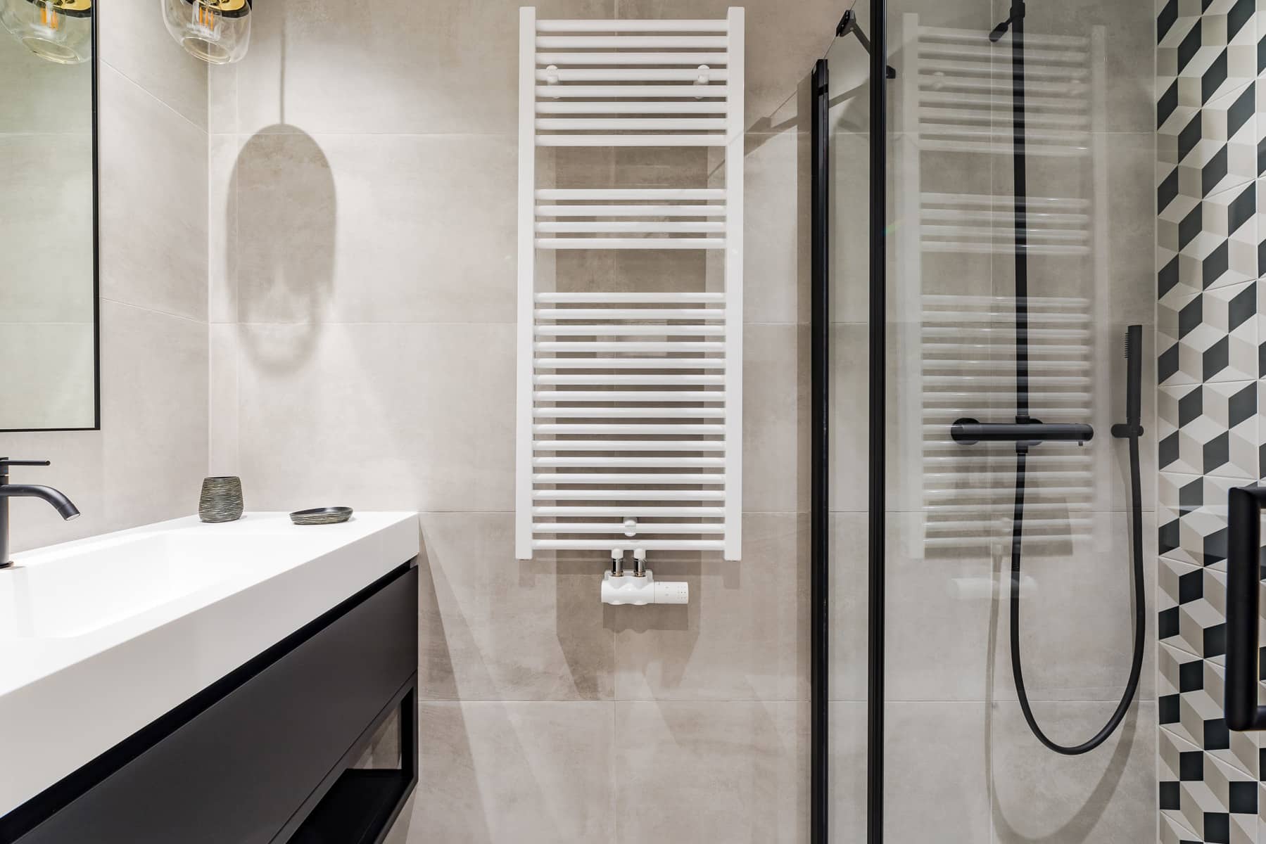 whise photo 9 Contemporary bathroom with a white ladder towel warmer, gray tiled walls, a glass shower enclosure, black fixtures and a black vanity.