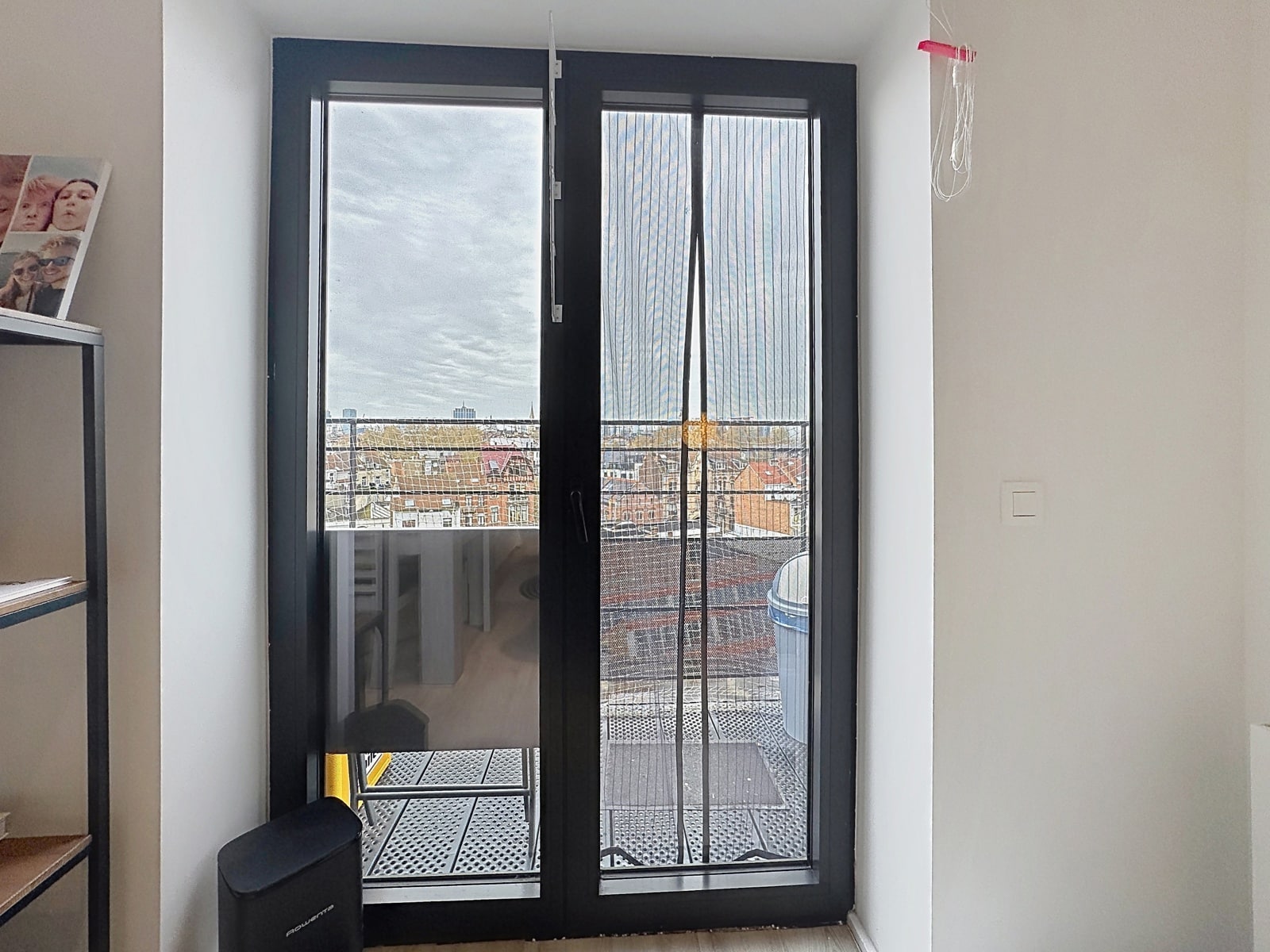 Balcon Avec Vue Urbaine – You Real Estate Agency Appartement lumineux avec balcon, porte vitrée et vue dégagée sur la ville.