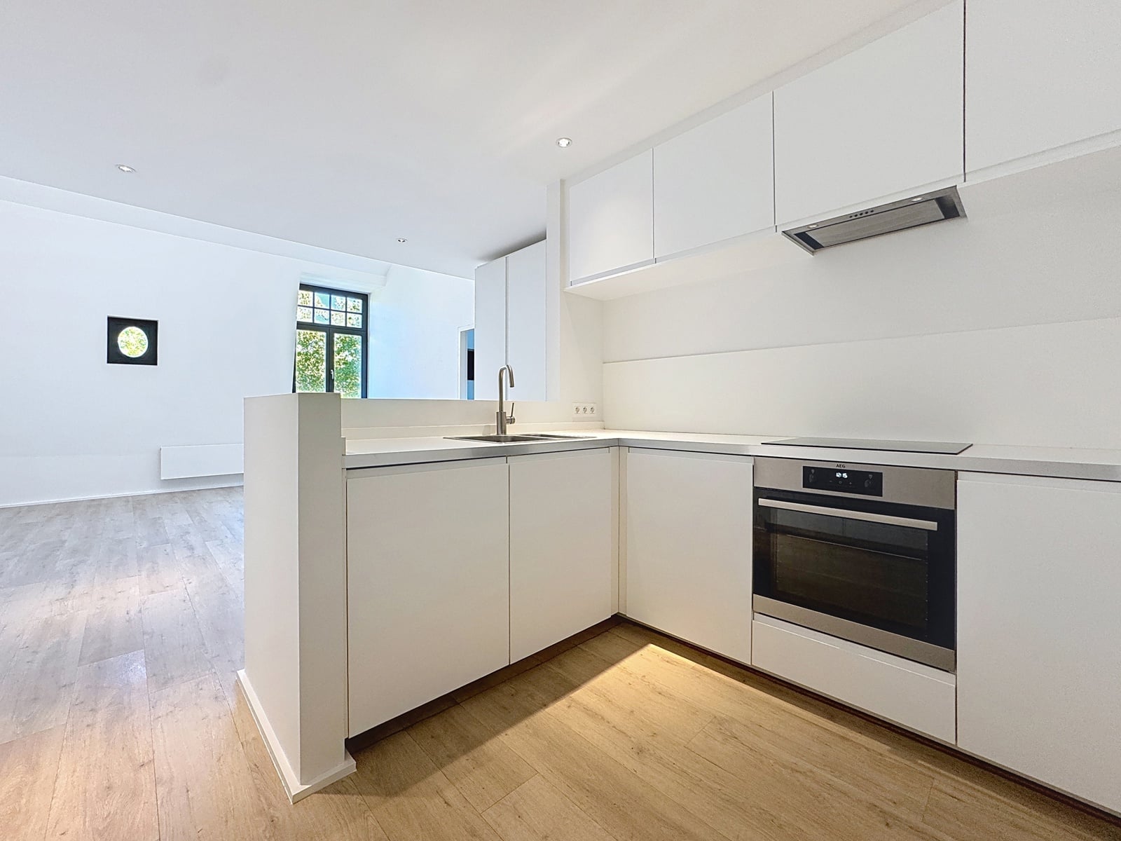 whise photo 4 Bright white modern kitchen with island, sink, and built-in oven under sleek range hood.