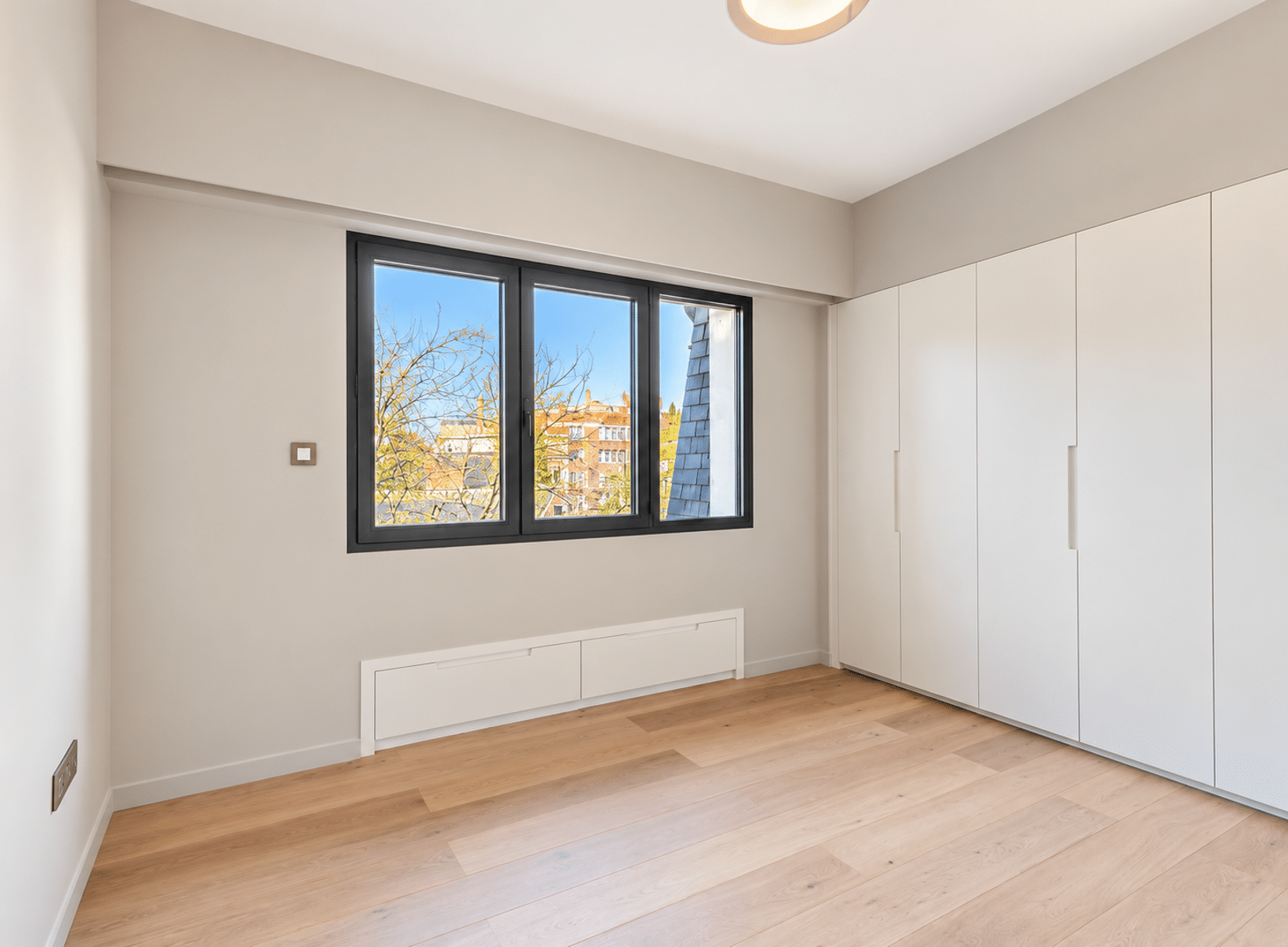 whise photo 23 Empty minimalist bedroom with light hardwood floors, white built-in wardrobes, and a large black-framed window.