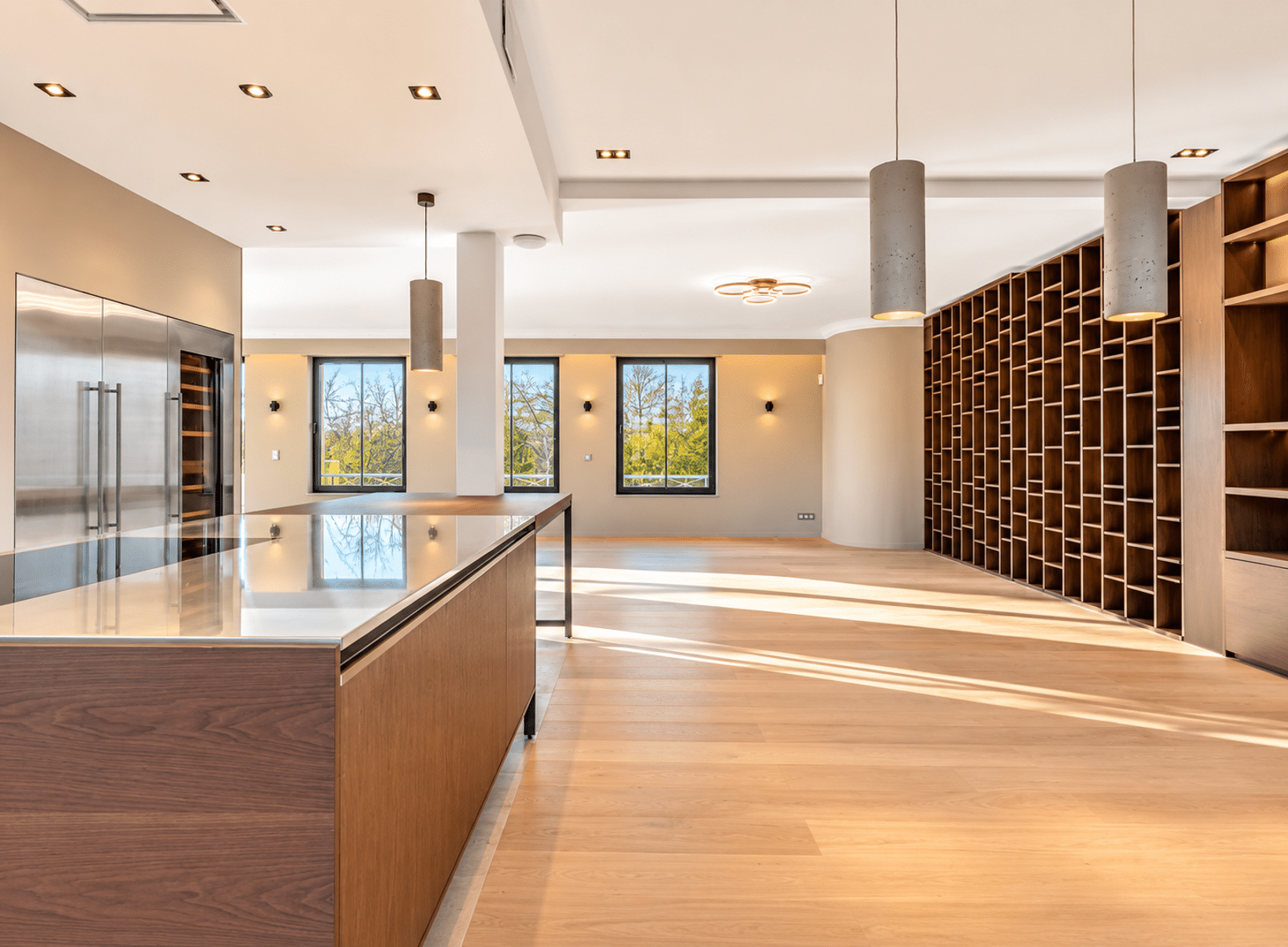 Cuisine Ouverte avec Îlot Central – You Real Estate Agency Cuisine ouverte moderne avec îlot central, salon lumineux et parquet en bois.