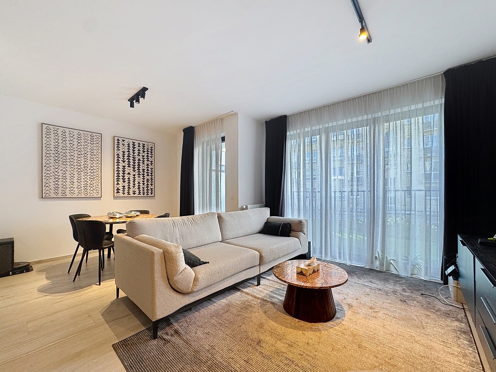 Bright living and dining room - You Real Estate Agency Modern living room and dining room in a bright apartment with large picture windows.