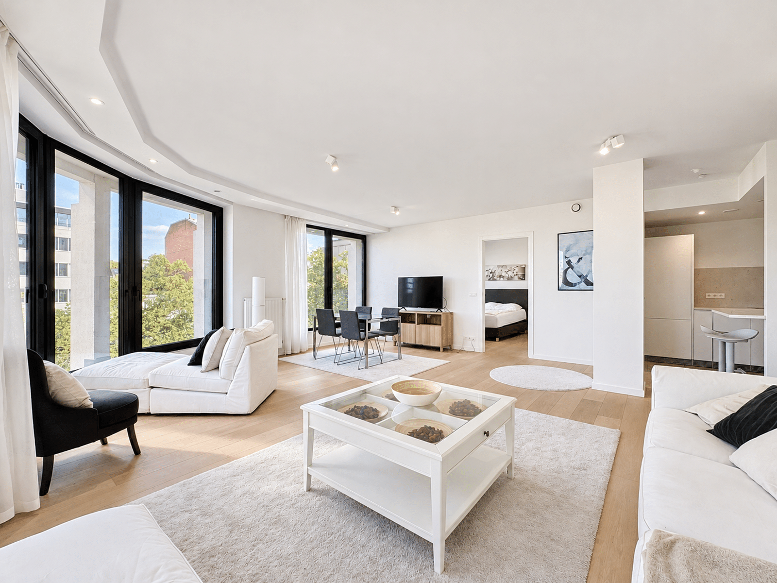 Séjour Ouvert et Lumineux – You Real Estate Agency Appartement lumineux avec salon ouvert, cuisine moderne et grandes baies vitrées.