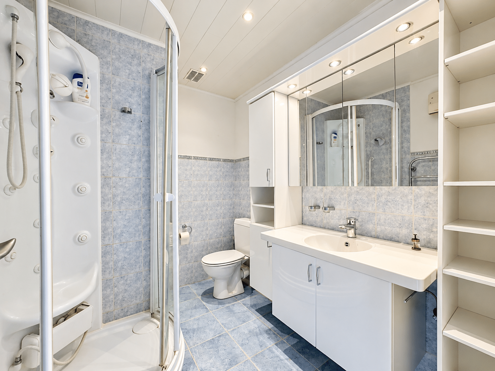 Salle de Bains Moderne avec Douche – You Real Estate Agency Salle de bains d’appartement moderne avec douche d’angle, meuble vasque et rangements.