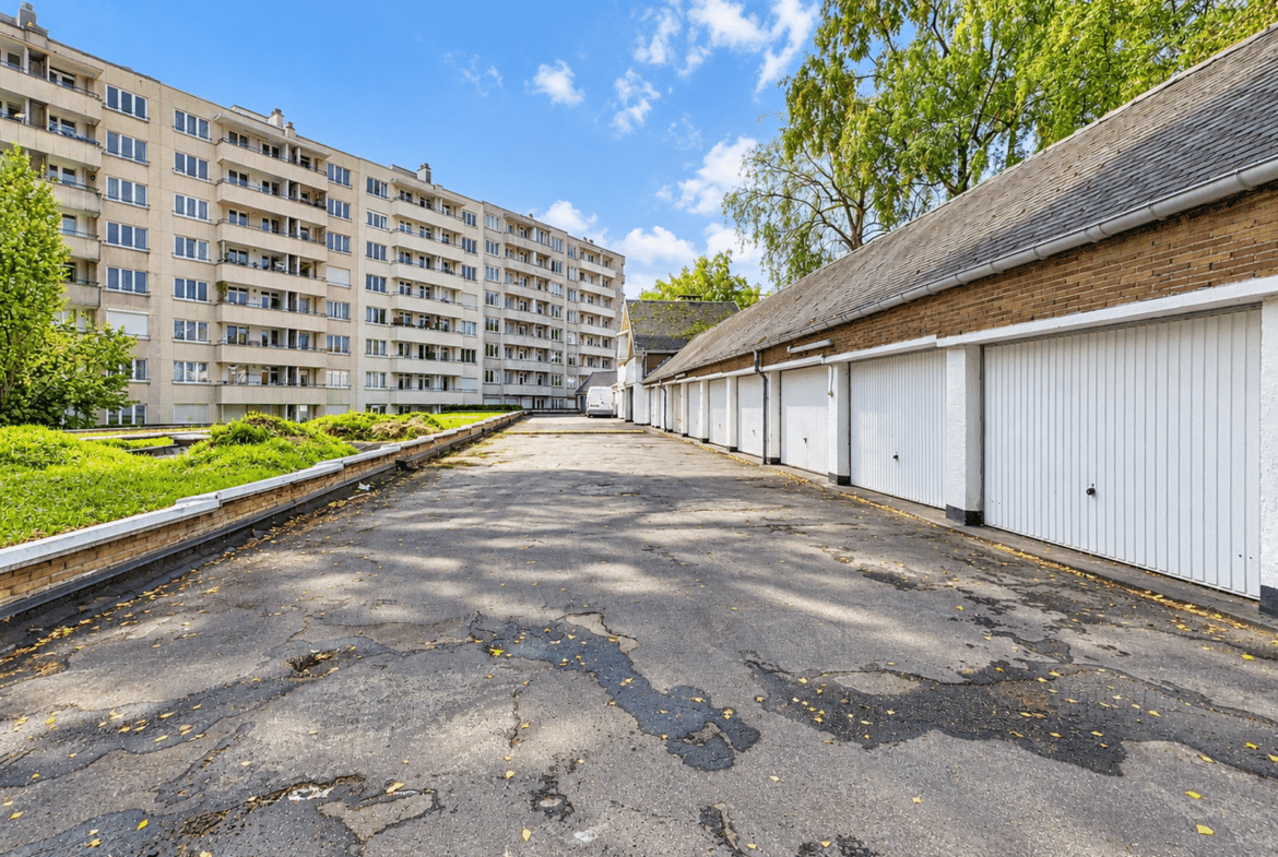 Cour intérieure résidentielle avec garages et immeuble d’appartements ensoleillé.