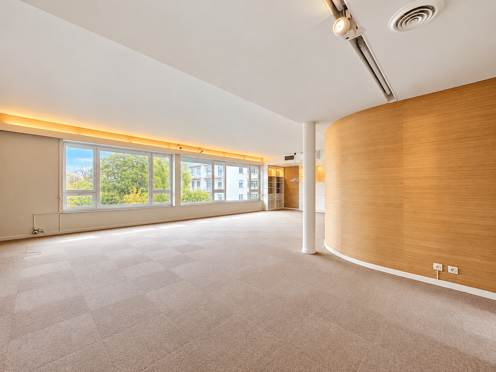 Salon Lumineux Avec Grandes Fenêtres – You Real Estate Agency Salon lumineux d’appartement avec grandes fenêtres et mur courbe en bois.