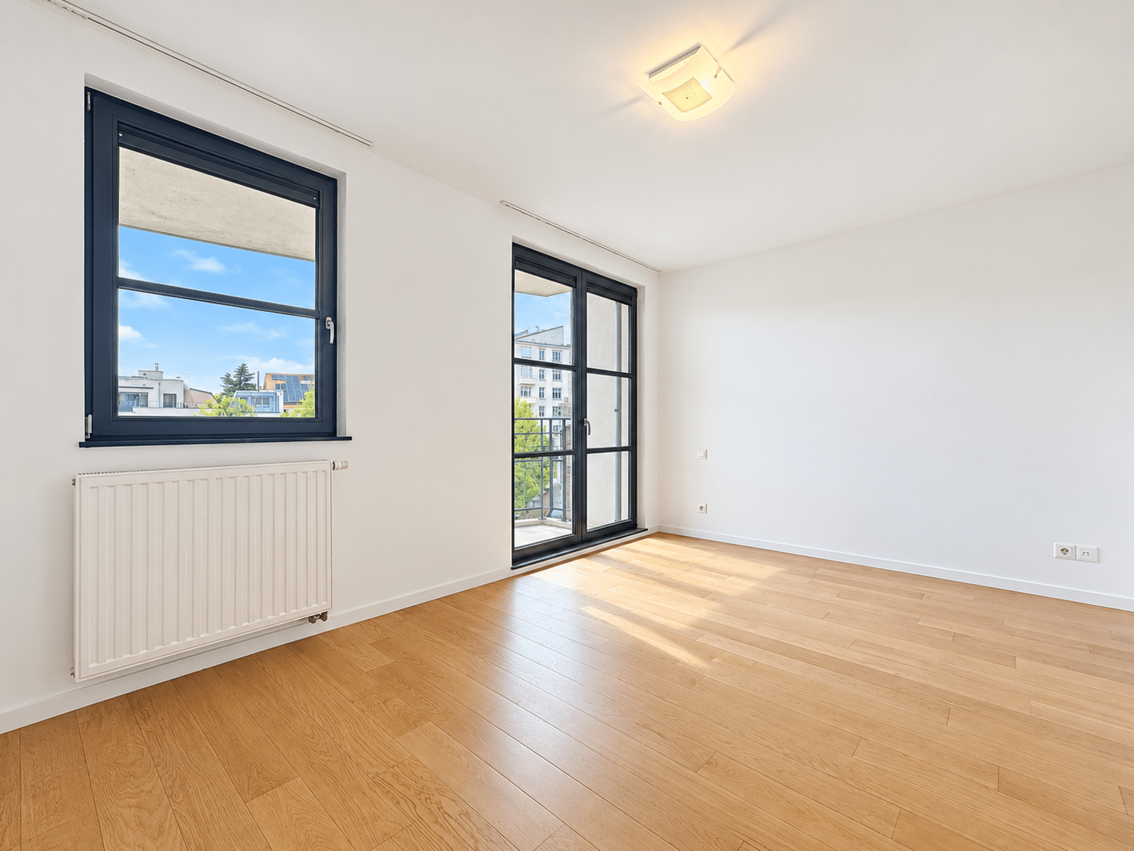 Salon Lumineux avec Balcon – You Real Estate Agency Salon lumineux d’appartement avec parquet, grande fenêtre et balcon.