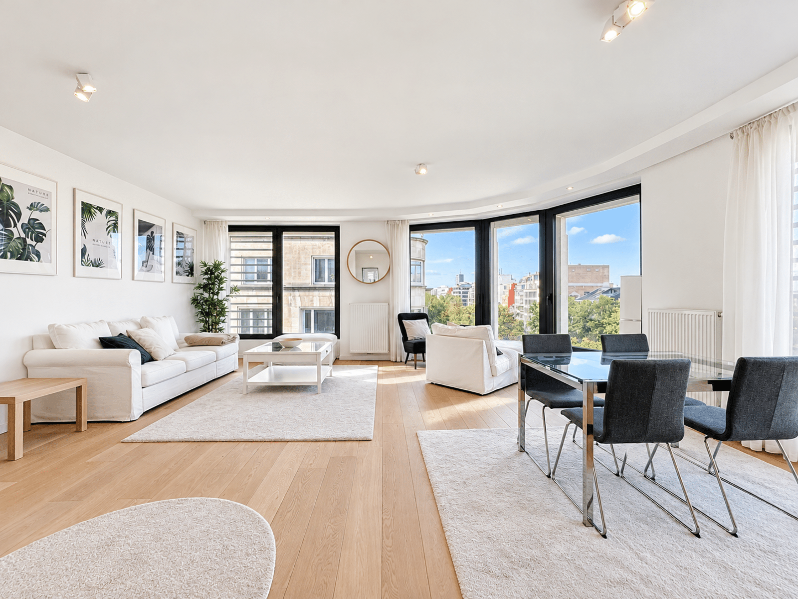Salon-Salle à Manger Lumineux – You Real Estate Agency Salon-salle à manger lumineux avec grandes fenêtres dans appartement moderne.