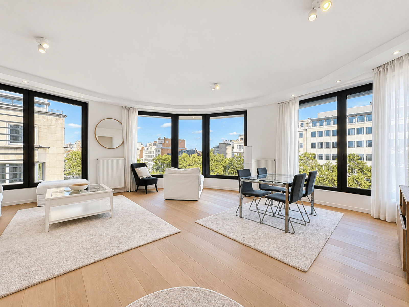 Salon et Salle à Manger Lumineux – You Real Estate Agency Salon et salle à manger lumineux d’un appartement moderne avec grandes fenêtres.