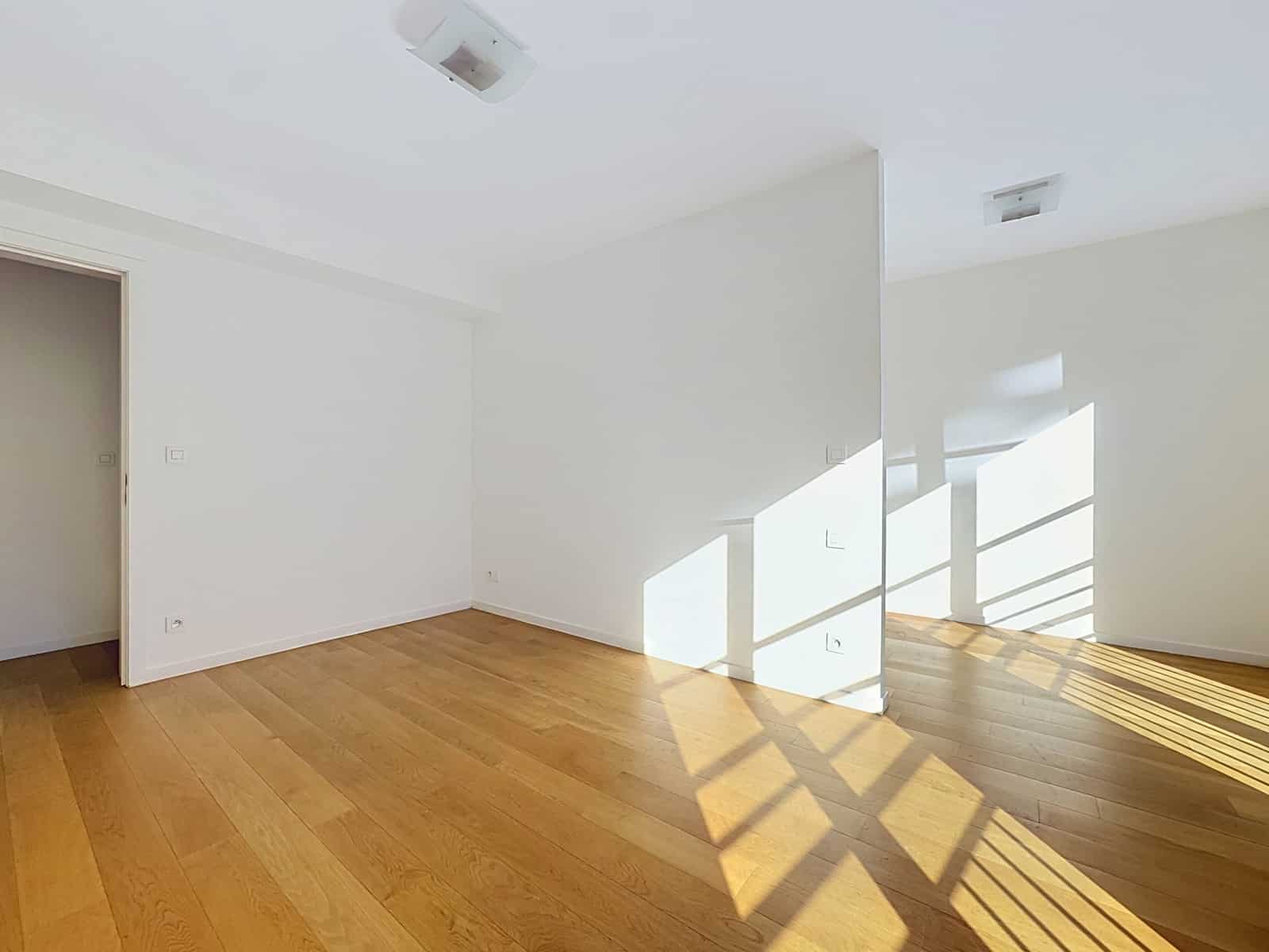 Bright living room with parquet floor - You Real Estate Agency Salon lumineux vide avec parquet en bois dans un appartement moderne.